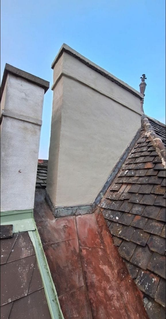 Frisch verputzter Fangkopf neben einem alten Rauchfangkopf auf einem Steildach