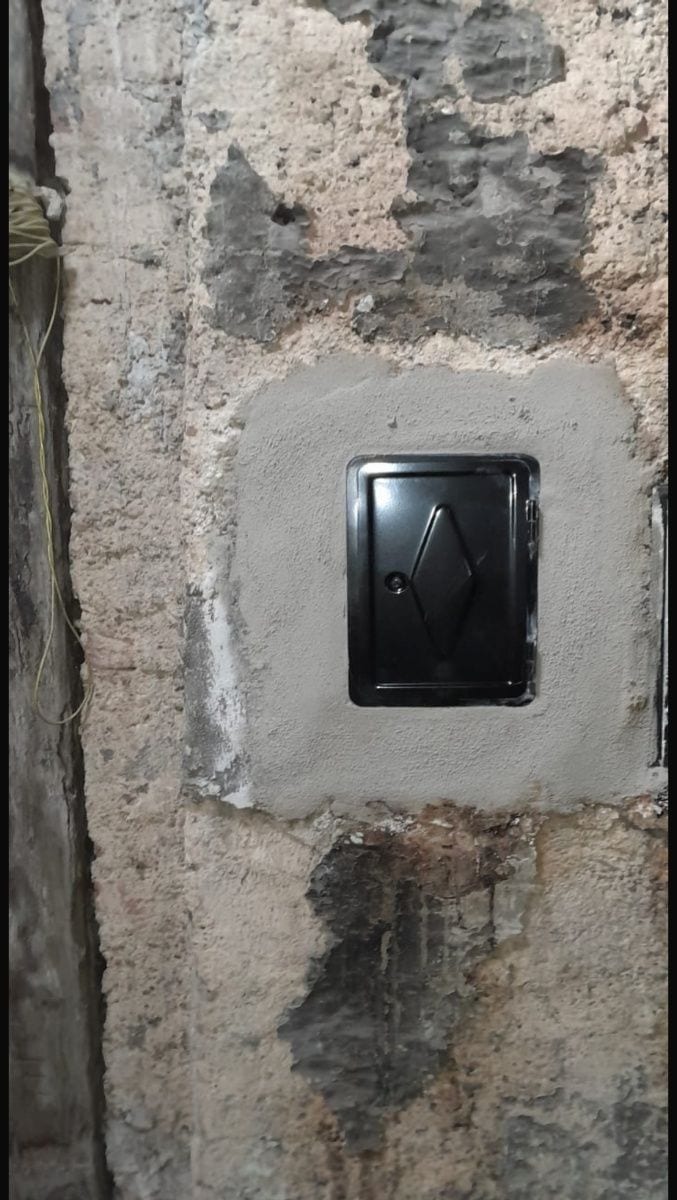 Neu eingebaute Kehrtür mit frischem Putzfeld an einem Rauchfang im Altbau