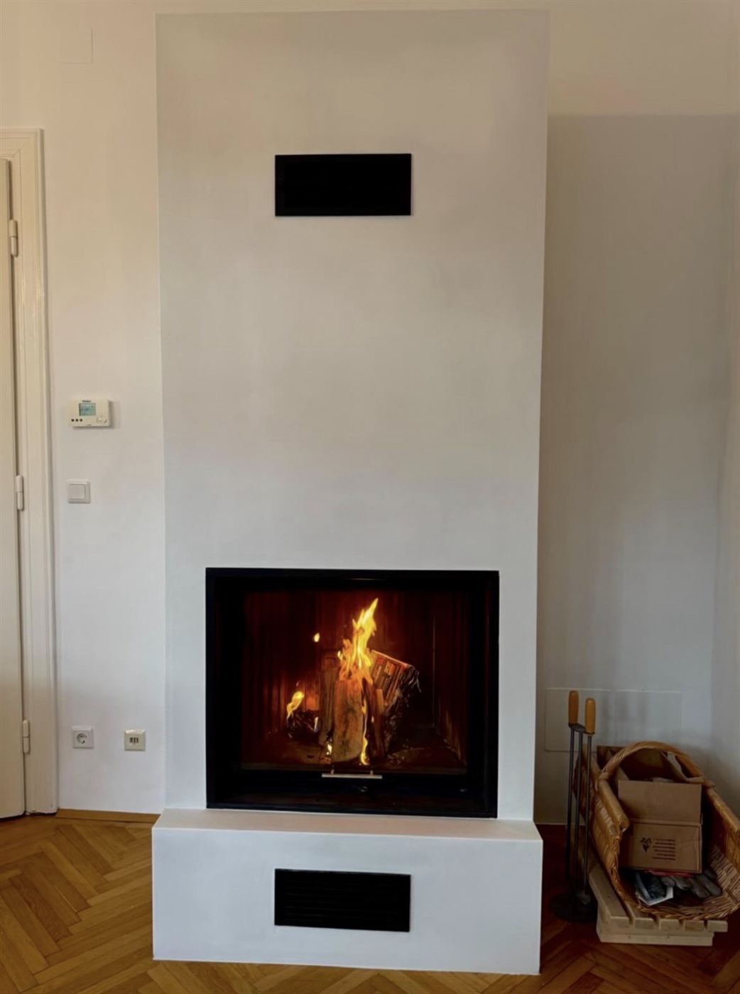 Moderner weißer Kaminofen mit brennendem Feuer im Altbau-Wohnzimmer