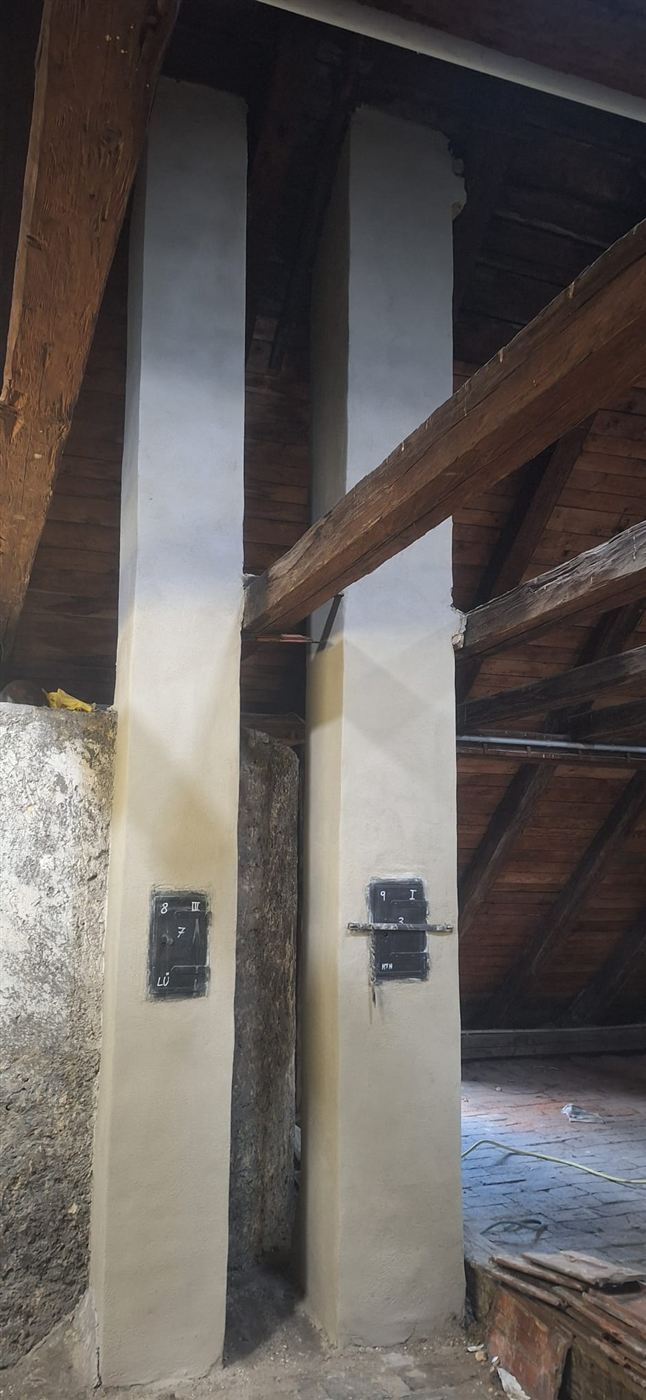 Zwei sanierte Wangenmauern zwischen historischen Holzbalken